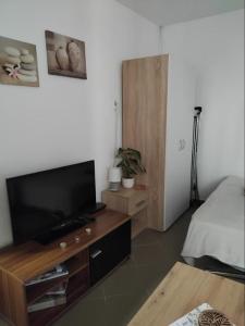 a living room with a flat screen tv and a bed at Apartman "Vuković" in Bizovac
