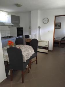 a kitchen with a table and chairs and a clock on the wall at Apartman "Vuković" in Bizovac