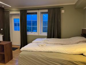 two beds in a room with two windows at Smart mini apartment with kitchen in Åmot