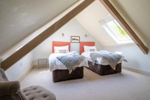 two beds in a attic bedroom with a roof at Peak Hall in Colkirk