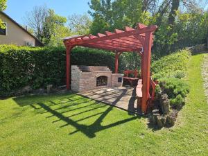 a wooden pergola with a fireplace in a yard at Waterside Cottage in Nagyrév