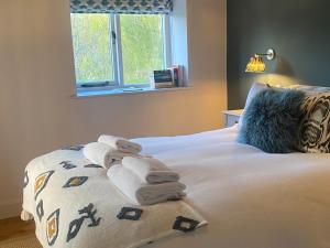 a bedroom with towels on a bed with a window at The Annexe, Cleveley Mill in Chipping Norton