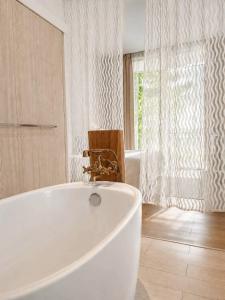 eine weiße Badewanne in einem Badezimmer mit Fenster in der Unterkunft White Wall Riverfront Hotel in Kamphaeng Phet + 35 Fotos