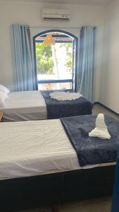 two beds in a room with a window at Santorini Suítes in Tamandaré