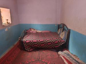 a small bedroom with a bed with a blanket on it at dar elkarzabi in Zagora