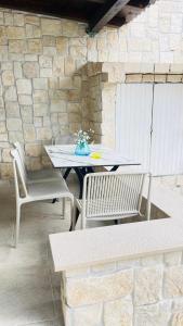a table and two chairs sitting next to a stone wall at Stonehouse-Pag in Povljana
