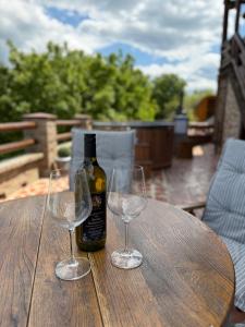 two wine glasses and a bottle on a wooden table at Wood house Marilla in Virovitica
