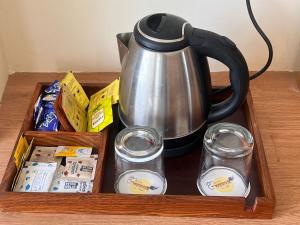 a tray with a tea kettle and containers of food at Hotel Radha Vallabh in Ukhimath