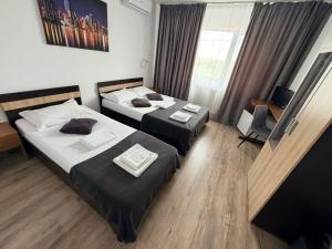 a hotel room with two beds and a television at Pensiunea Gerard 2 Mai Camere Moderne cu baie privata, la 250 M de plaja ,Foisor, Parcare & WIfi Gratuit in 2 Mai