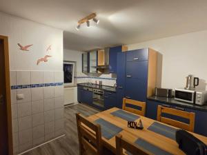 a kitchen with blue cabinets and a wooden table with chairs at Ferienwohnung MOIN in Osdorf
