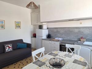 a kitchen and a living room with a couch and a table at Les Chalets la Plage - Etape Vacances in Portiragnes