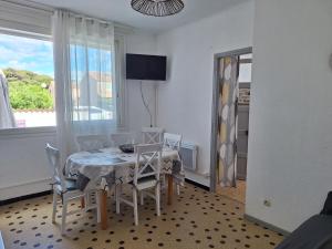 a dining room with a table and chairs and a window at Les Chalets la Plage - Etape Vacances in Portiragnes