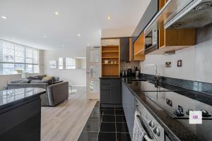 a kitchen with black and white counter tops and a living room at Brighton central stylish stays. Walk to the beach. in Brighton & Hove