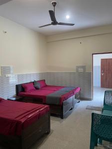 a room with two beds and a ceiling fan at Hotel Badri Palace in Rishīkesh