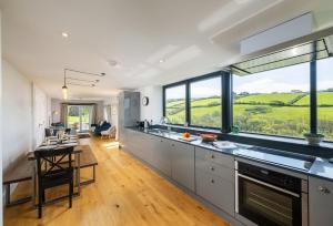a kitchen with white cabinets and a large window at Pentreath in Bude