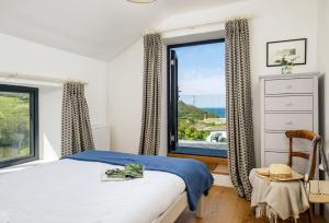 a bedroom with a bed and a large window at Pentreath in Bude