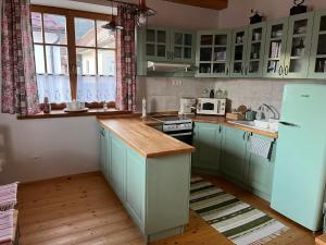 a kitchen with green cabinets and a white refrigerator at Chalúpka Barborka in Lúčky