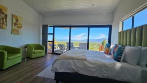 a bedroom with a large bed and two green chairs at Walkerbay Dunes Lodge in Stanford