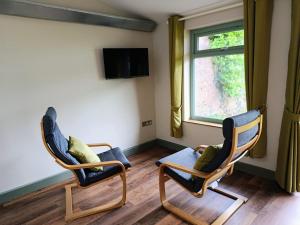 two chairs and a table in a room with a window at Lodge Two The Old Gasworks in Milverton