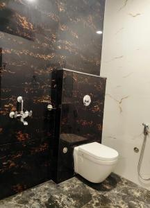 a bathroom with a toilet and a black wall at Hotel Kashi Bliss in Varanasi