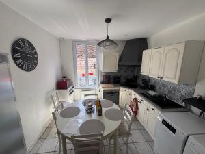 a kitchen with a table and chairs and a clock at Gîte du Palais 3 étoiles in Châteauneuf-sur-Cher