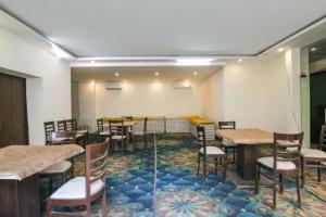 a dining room with tables and chairs and a rug at FabHotel Signature Luxe Inn - Chhattarpur in New Delhi