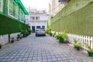 a car parked on a brick sidewalk next to a green wall at FabHotel Signature Luxe Inn - Chhattarpur in New Delhi