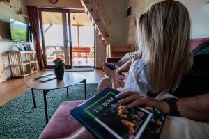 a woman sitting on a couch reading a book at a Ficak in Miskolc