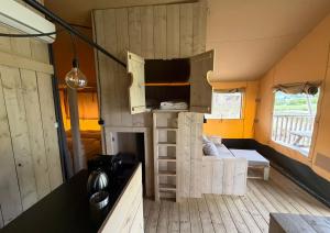 a room with a living room with a stove in a house at Safaritent Ranger Lodge in Kesteren