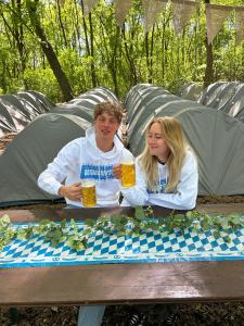 a man and woman sitting at a picnic table with beer at Munich Oktoberfest Accommodation Party Camping Experience in Munich