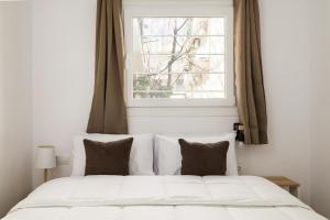 a white bed with two pillows in front of a window at Ourania Lofts and Suites in Thessaloniki