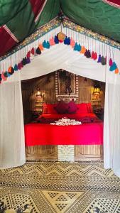 a bedroom with a red bed in a tent at Tente et Restaurant ElBey in Douz +70 photos