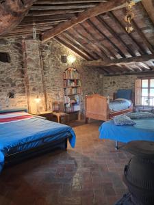 a bedroom with two beds and a stone wall at Attic with balcony at Locanda del Capo in Capannori