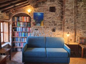 a blue couch in a living room with bookshelves at Attic with balcony at Locanda del Capo in Capannori