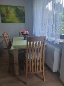 a dining room table with two chairs and a vase with flowers at Apartament Flora in Mahlberg