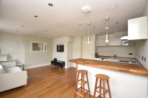 a kitchen and living room with a counter and stools at Flat 4, 15 Ethelbert Square CT8 8SR in Westgate-on-Sea