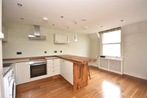 a kitchen with a wooden table in a room at Flat 4, 15 Ethelbert Square CT8 8SR in Westgate-on-Sea +8 photos