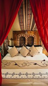 a bedroom with a large bed with red curtains at Tente et Restaurant ElBey in Douz