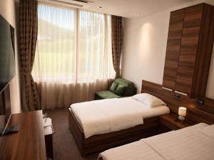 a hotel room with two beds and a chair and a window at Hotel Luka's in Berane