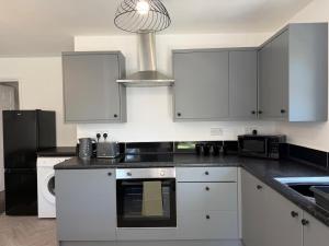 a kitchen with white cabinets and a stove top oven at Gatwick 2 Bed Apartments Free Parking in Horley