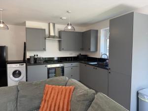 a living room with a couch and a kitchen at Gatwick 2 Bed Apartments Free Parking in Horley