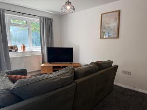 a living room with a couch and a flat screen tv at Gatwick 2 Bed Apartments Free Parking in Horley