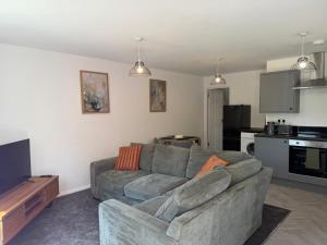 a living room with a gray couch and a kitchen at Gatwick 2 Bed Apartments Free Parking in Horley +67 photos