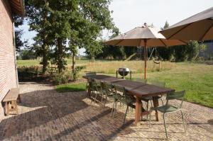 a wooden table and chairs with an umbrella at Vakantiewoning Hof ter Heidje in Maarkedal