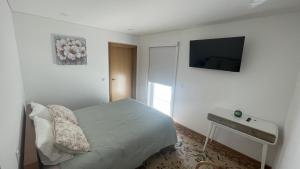 ein Schlafzimmer mit einem Bett und einem Fernseher an der Wand in der Unterkunft Quinta do Plaino in Mões