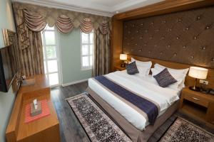 a bedroom with a large bed and two windows at Hotel Britania in Tirana