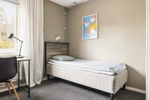 a bedroom with a bed and a desk and a window at Hakefjorden by Workershotel in Källsby