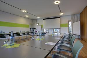 a conference room with tables and chairs and a screen at eXo Fly Level 4 Hotel Stuttgart-Flughafen in Ostfildern