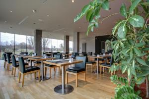 a restaurant with wooden tables and chairs and a large plant at eXo Fly Level 4 Hotel Stuttgart-Flughafen in Ostfildern