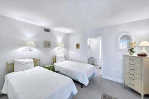 a white bedroom with two beds and a dresser at Lighthouse Point A311 in Sanibel +28 photos